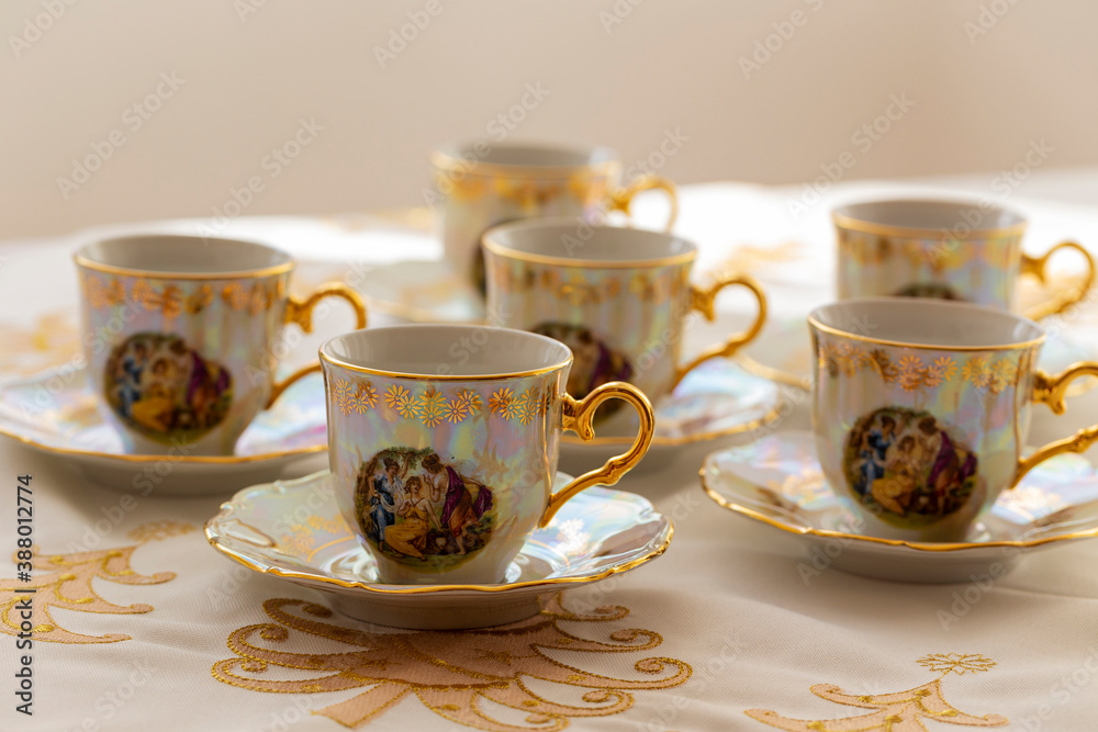 Fototapeta premium A set of six festive, decorated, painted cups built on a gold embroidered Christmas tablecloth.