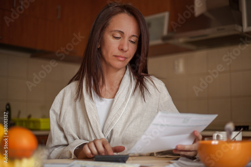 Serious woman preparing home budget, using calculator