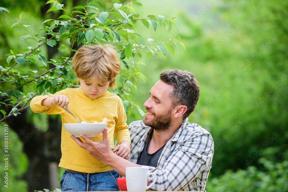 Fototapeta premium Best weekend ever. healthy food and dieting. Dairy products. family dinner time. Morning breakfast. Vegetarian diet. happy fathers day. Little boy with dad eat cereal. father and son eating outdoor