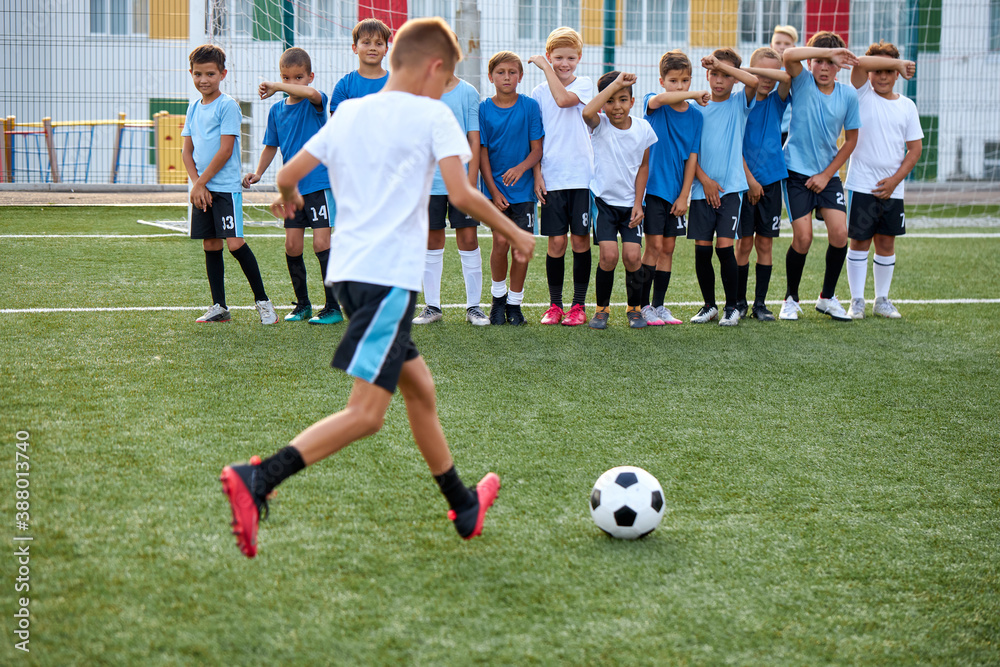 sportive child boy in uniform kicking ball, they have penalty in this round. kids play football, competition in stadium, in field