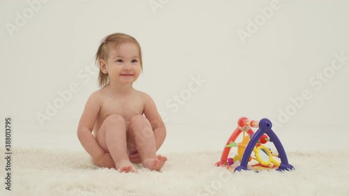 Happy little girl in diaper is playing toys. Slow motion