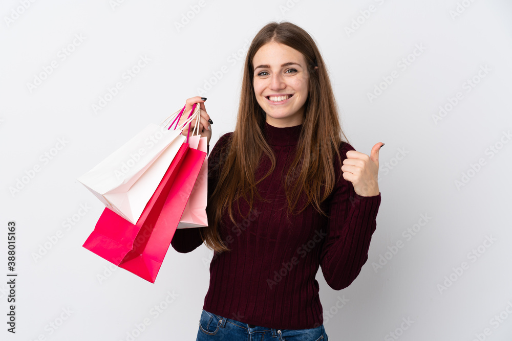 Young woman over isolated white background holding shopping bags and with thumb up