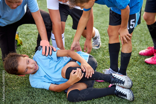 little caucasian boy fell to his knee, ache in joints during football game outdoors, injury during sport competition