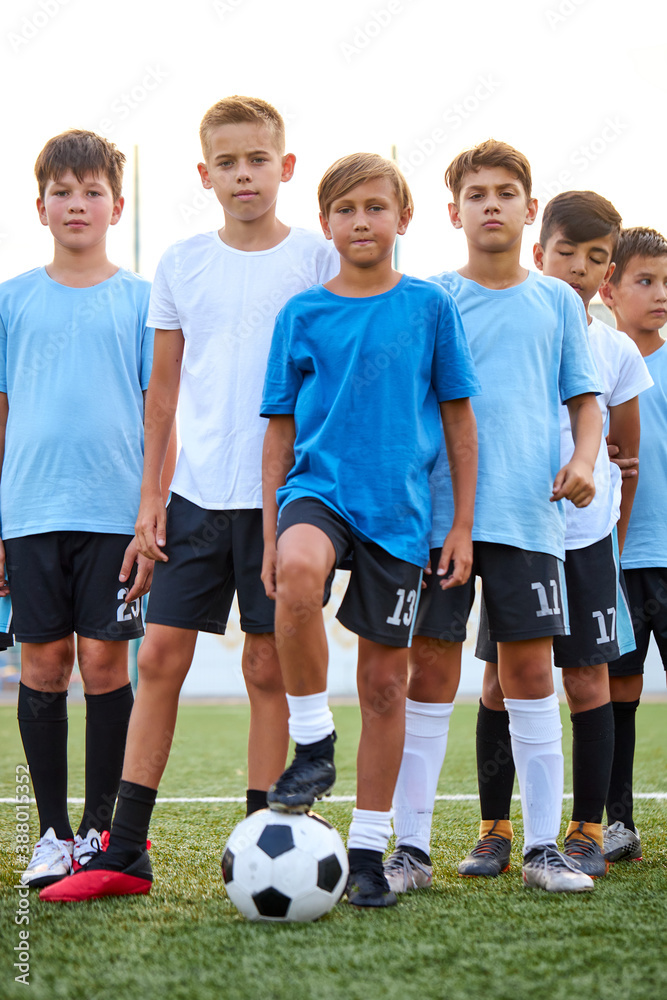 portrait of confident team of young football players posing at camera, athletic boys in uniform going to play football or soccer. in stadium portrait of confident team of young football players posing at camera, athletic boys in uniform going to play football or soccer. in stadium