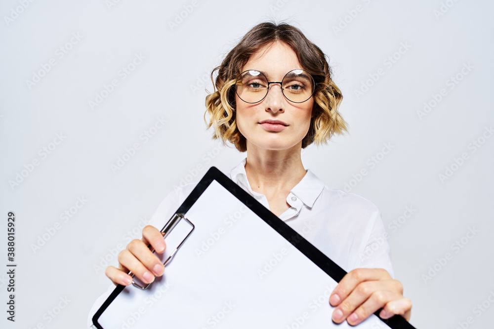 Business woman with a folder of white documents in her hand on a light background And hairstyle glasses model Business woman with a folder of white documents in her hand on a light background And hairstyle glasses model