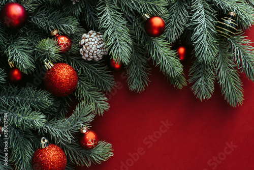 Space for text between Christmas tree branches with Christmas decorations and balls on a red background. Christmas composition. Happy New Year. Space for text