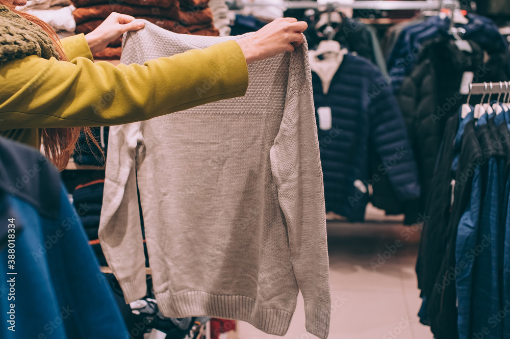 The girl holds clothes in the hands in the supermarket.