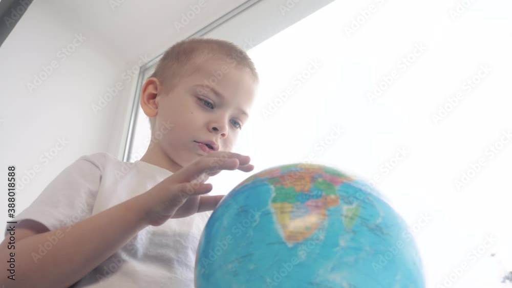 boy studies globe. education travel tourism concept. kid twists the globe lifestyle sits on a window sill. child looking for a country on a globe map . world map geography study boy studies globe. education travel tourism concept. kid twists the globe lifestyle sits on a window sill. child looking for a country on a globe map . world map geography study