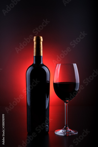wine bottle with full glass black background and red