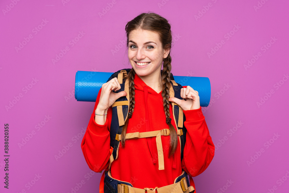 Young mountaineer girl with a big backpack over isolated purple background proud and self-satisfied Young mountaineer girl with a big backpack over isolated purple background proud and self-satisfied