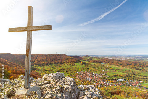 Summit cross on a rocky mountain peak overlooking beautiful autumn landscape in the Swabian Jura