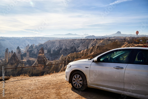 Car on high observation deck for looking on strange landscape in Cappadocia valley with yellow mountains, rocks and hills and blue sky with white clouds