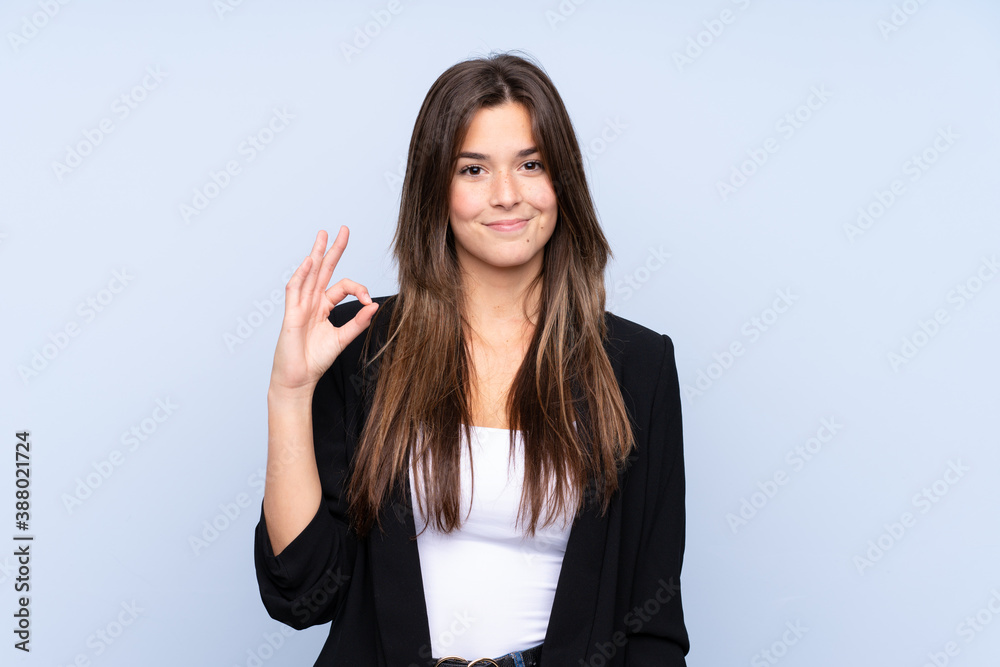 Young Brazilian business woman over isolated blue background showing an ok sign with fingers Young Brazilian business woman over isolated blue background showing an ok sign with fingers
