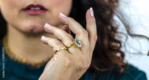 Detail of white woman s hand with luxurious golden rings with precious stones. Topaz and blue sapphire.