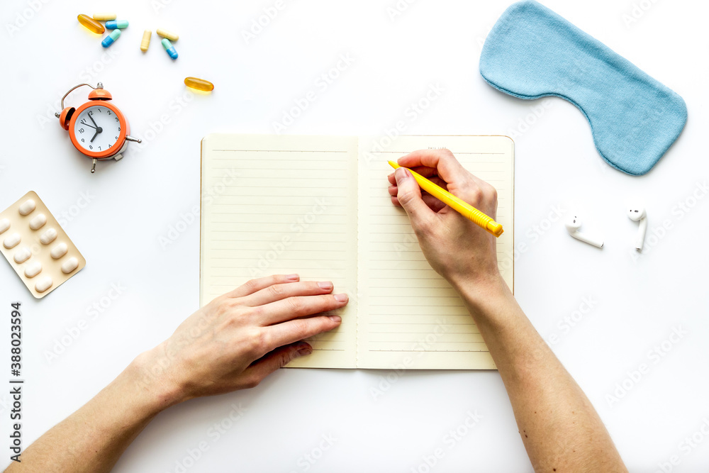 Female hand write in notebook - day plan before sleeping. Top view Female hand write in notebook - day plan before sleeping. Top view