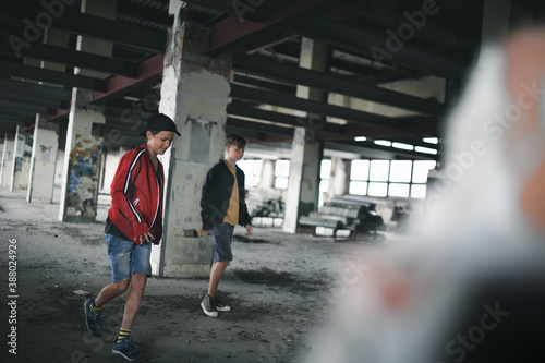 Teenagers boys indoors in abandoned building, walking.