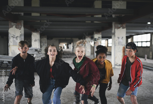 Group of teenagers girl gang standing indoors in abandoned building, shouting.