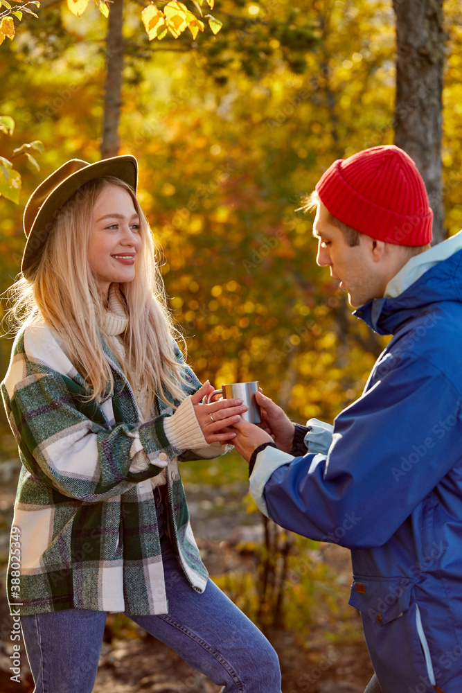 happy caucasian couple keep warm up with tea during travel in forest, journey pf couple is going well, they are in good mood happy caucasian couple keep warm up with tea during travel in forest, journey pf couple is going well, they are in good mood