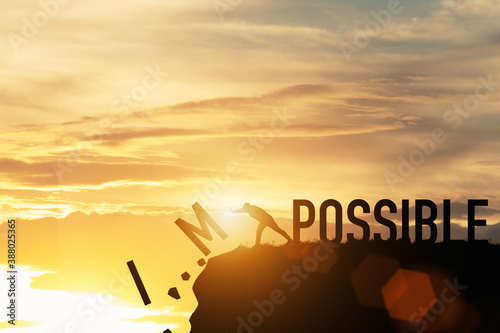 Businessman push impossible wording to possible wording on top of mountain with sunlight. Positive mindset concept. photo