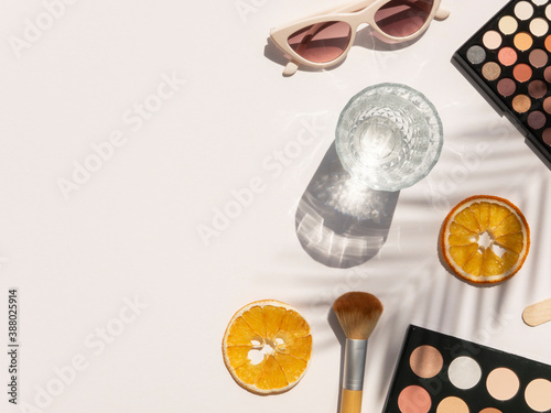 Beauty desk top view with cosmetics, palm shadows and copy space