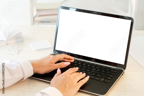 Distance work. Online communication. Business chat. Unrecognizable female hands typing on laptop blank screen on desk light workplace interior copy space.