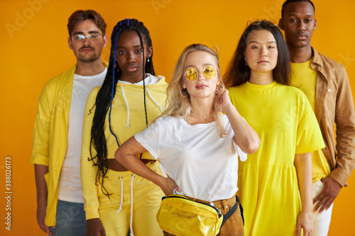 confident diverse mult-ethnic group of people stand together, isolated on yellow background, stylish african caucasian and asian youth
