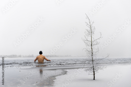 Fototapeta Naklejka Na Ścianę i Meble -  Man going ice swimming into a frozen lake in winter
