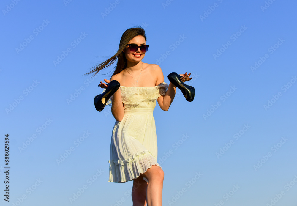 Freedom. Girl in sunglasses copy space. Towards summer. Afterparty concept. Woman sunrise carry high heels in hand. Woman on sunny morning blue sky. Summer holidays. Model tender summer dress Freedom. Girl in sunglasses copy space. Towards summer. Afterparty concept. Woman sunrise carry high heels in hand. Woman on sunny morning blue sky. Summer holidays. Model tender summer dress