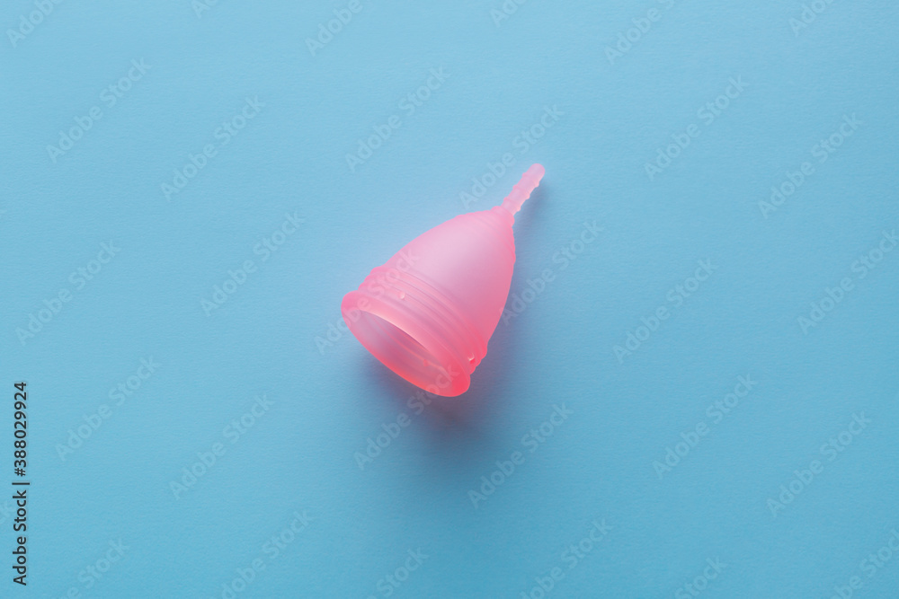 pink menstrual cup on blue background, intimate hygiene, menstruation