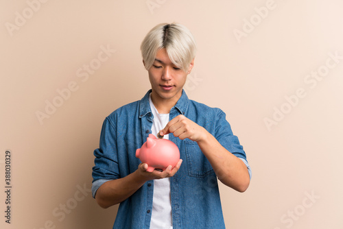 Young asian man over isolated background holding a big piggybank