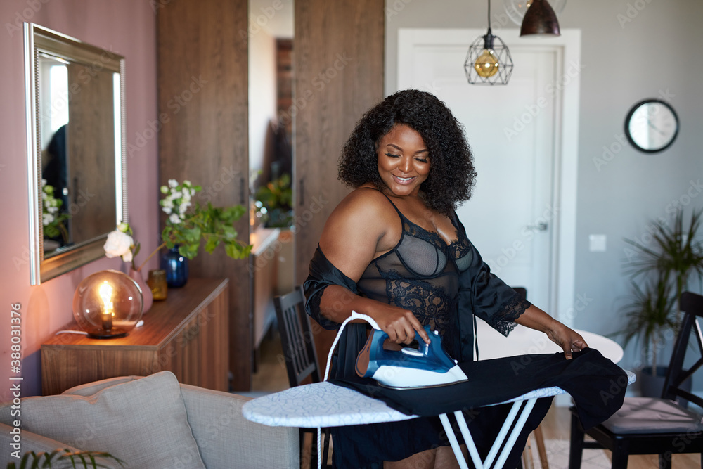 adorable african american overweight woman ironing clothes at home, enjoy this process in the morning. in underwear adorable african american overweight woman ironing clothes at home, enjoy this process in the morning. in underwear