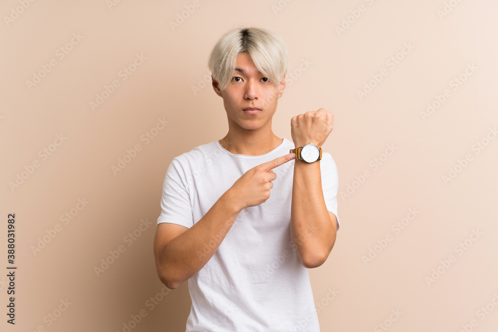 Young asian man over isolated background showing the hand watch with serious expression Young asian man over isolated background showing the hand watch with serious expression