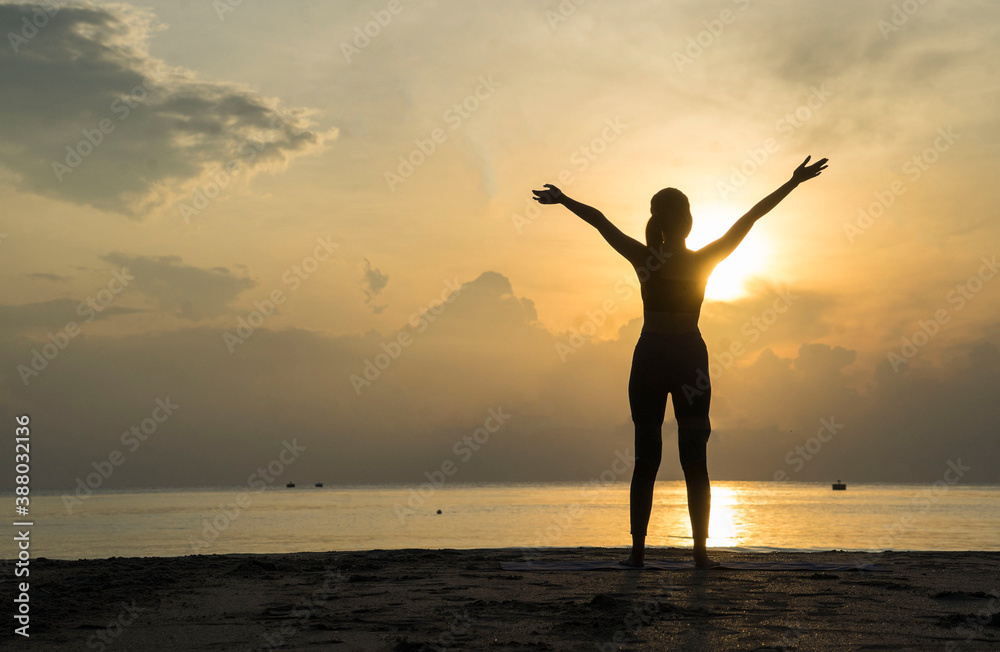 Silhouette of Asian girls stand with arms raised to feel free  and enjoying  life on the beach at sunrise  in morning .Freedom  and Wellbeing concept.