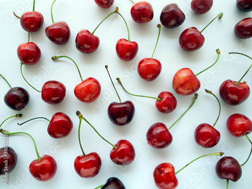 Ripe red cherry with twigs evenly distributed over a white background. Food background with berries.