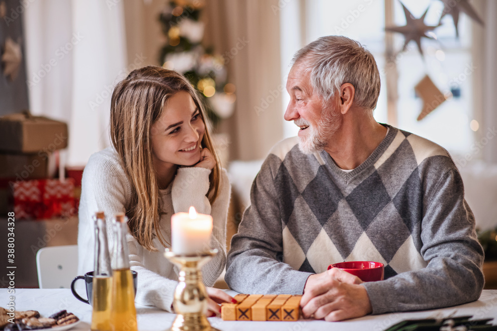 Φωτογραφία Young woman with grandfather indoors at home at Christmas, playing board games