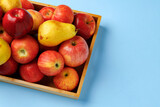 Wooden box with apples and pears on blue background