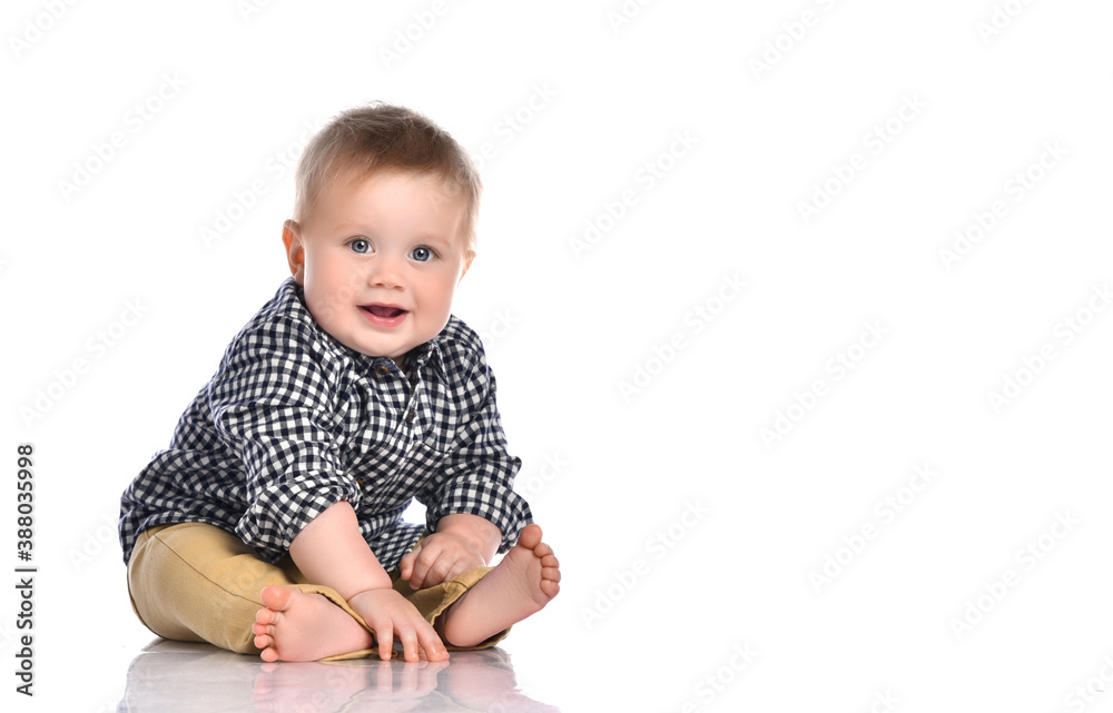 Funny baby boy sitting barefoot in a checkered shirt and pants. Funny baby boy sitting barefoot in a checkered shirt and pants.