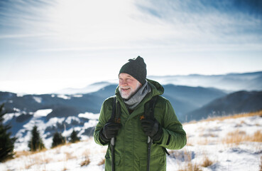 Portrait of senior man standing in snow-covered winter nature.