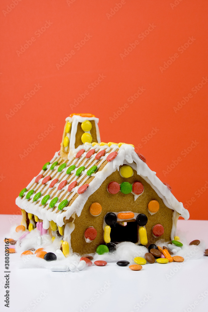 Naklejka premium Studio photo of gingerbread house for Christmas, red background.