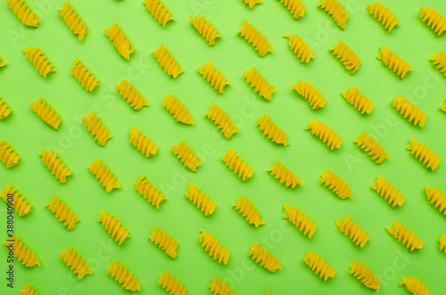 Top view of dry fusilli spiralle pasta on the  green surface as a background