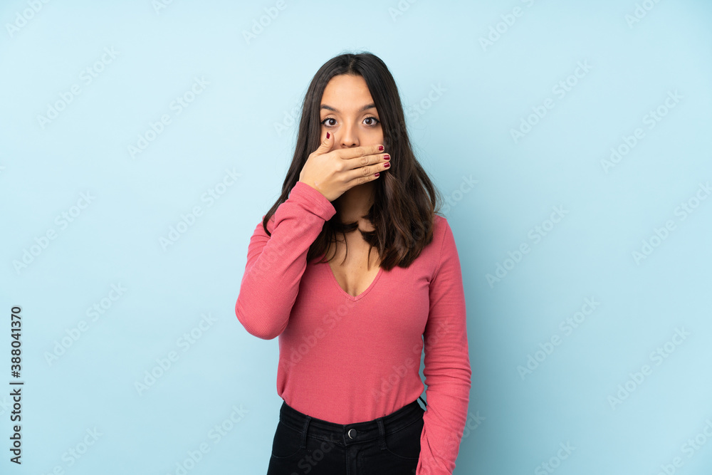 Young mixed race woman isolated on blue background covering mouth with hands Young mixed race woman isolated on blue background covering mouth with hands