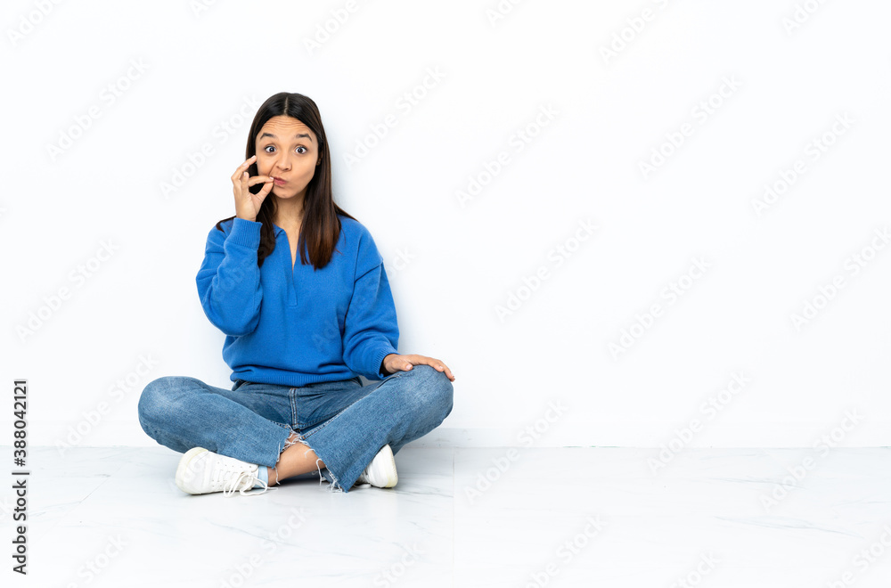 Young mixed race woman sitting on the floor isolated on white background showing a sign of silence gesture Young mixed race woman sitting on the floor isolated on white background showing a sign of silence gesture