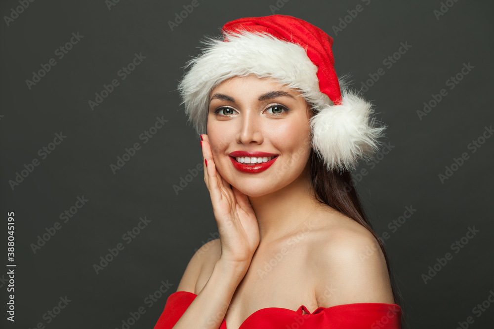 Cute young woman in Santa hat smiling on black background. Christmas model portrait Cute young woman in Santa hat smiling on black background. Christmas model portrait
