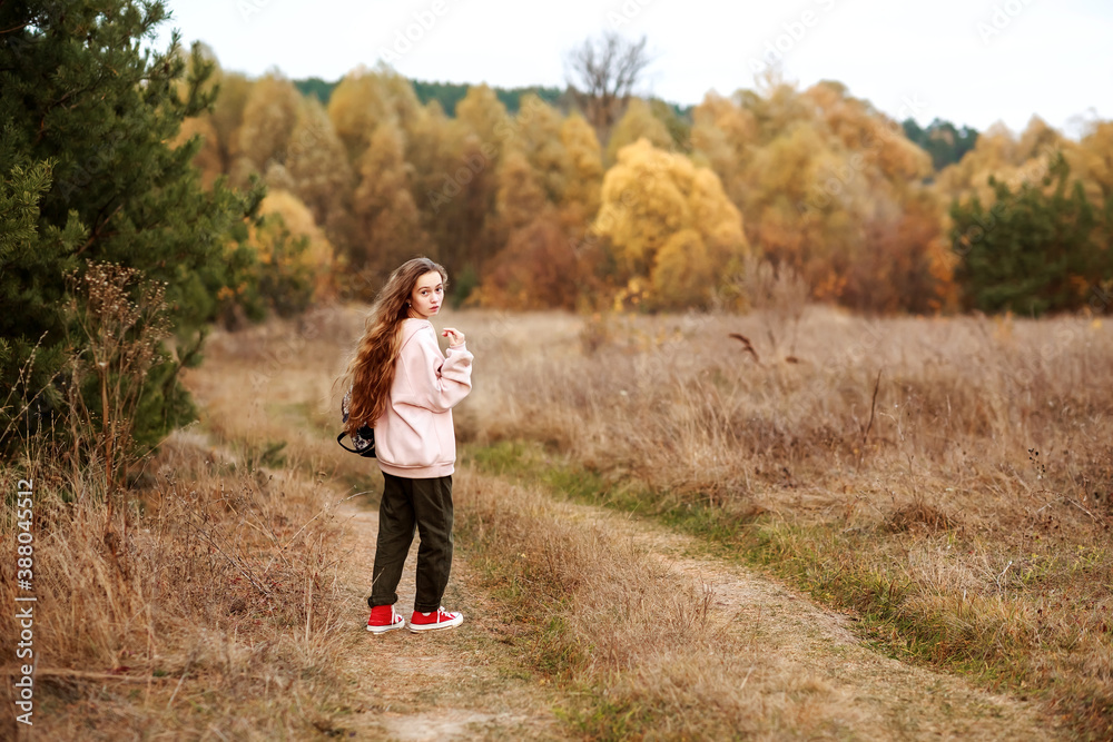 Portrait of a teenage girl in casual clothes on the background of an autumn landscape.