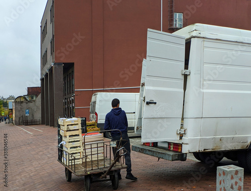 loader unloads a cart with crates in the market