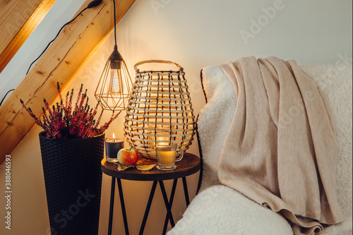 Fotografie Cozy sheepskin sherpa textile cover blanket on sofa, small side table with wood lantern candle burning, black metal wire spiral led bulb illuminated