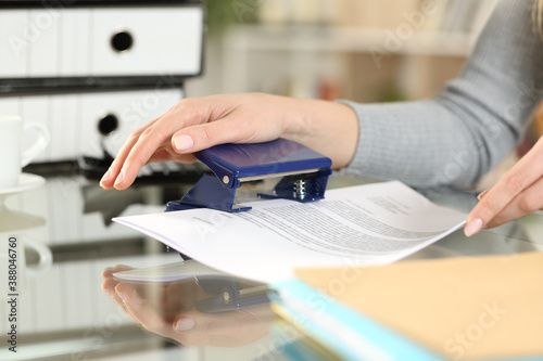 Woman hands doing holes with paper punch on documents photo