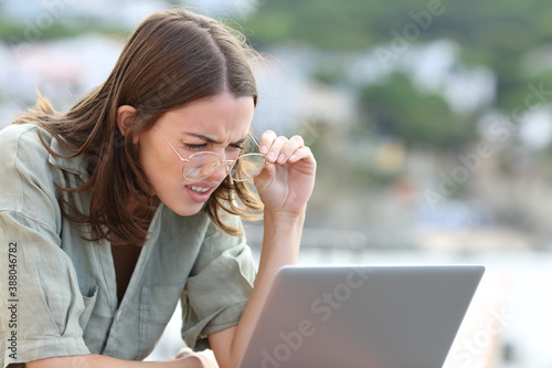 Woman forcing sight wearing eyeglasees reading laptop