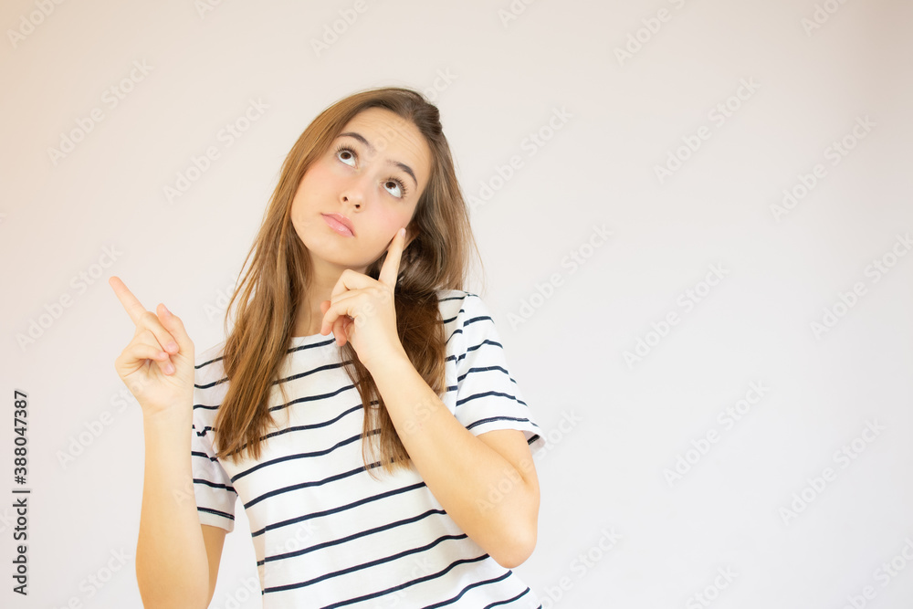 Portrait of a happy young girl dressed in red striped t-shirt pointing fingers up at copy space isolated over white background Portrait of a happy young girl dressed in red striped t-shirt pointing fingers up at copy space isolated over white background
