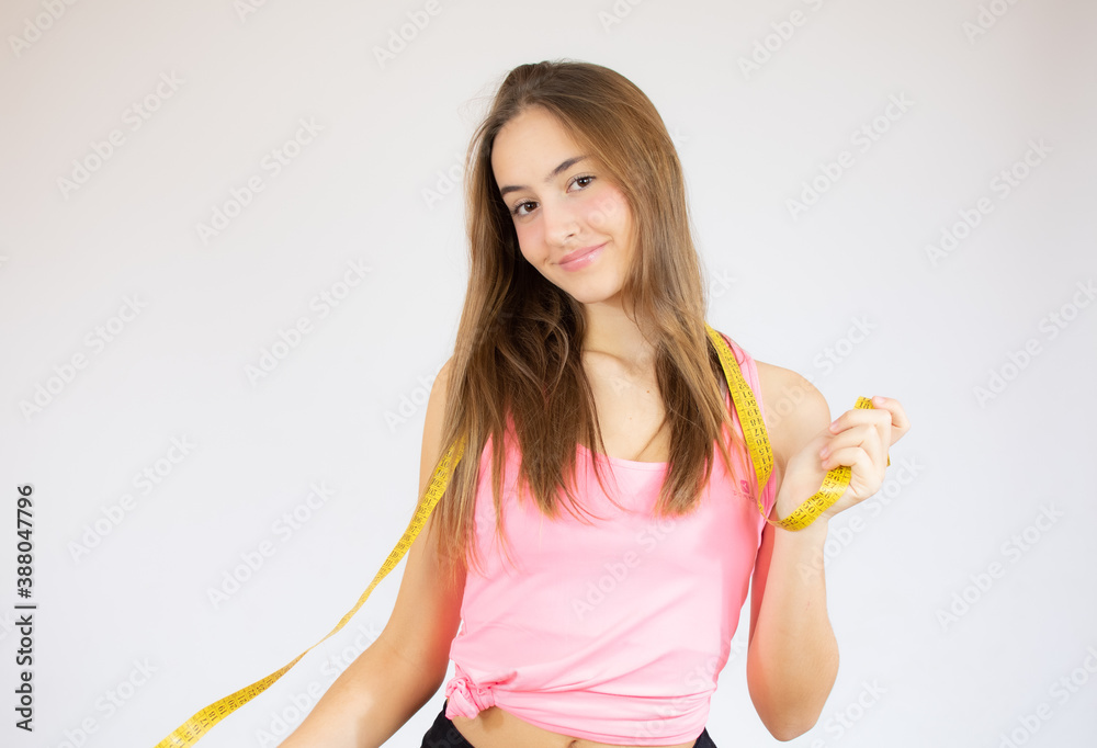 Photo of young fit woman cheerfully smiling and holding measure tape, isolated on white background Photo of young fit woman cheerfully smiling and holding measure tape, isolated on white background